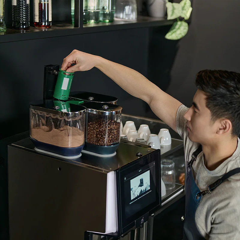 Mitarbeiter setzt einen WMF AutoClean Reinigungsbeh&auml;lter in eine professionelle Kaffeemaschine ein